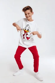 Smiling boy in cartoon duck tee and red pants posing playfully.