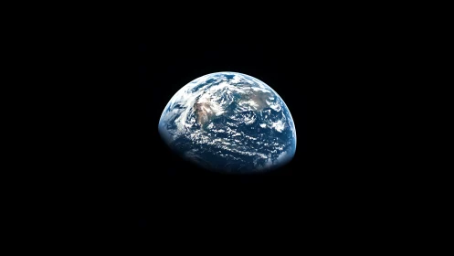 Earth is viewed as a partially sunlit sphere in deep space