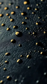 Golden droplets scatter across dark textured surface in macro