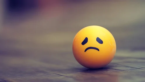 Melancholic yellow sphere on blurred wooden plane surface.