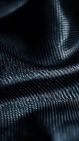 Textured dark fabric folds shimmer under soft light.
