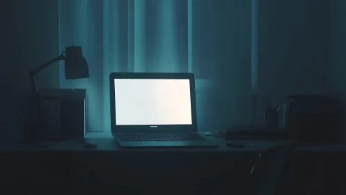Glowing laptop screen illuminates a silent midnight workspace.