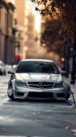 Lowered silver Mercedes coupe stands on wet urban street at dusk