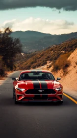 Red striped sports car on two-lane mountain road front view.