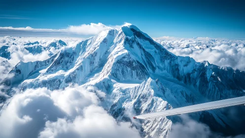Snowcapped alpine peak rises through bright sunlit clouds.