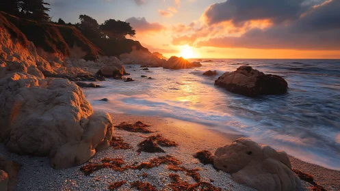 Sunlit rocky shoreline with vibrant orange coastal sunset.