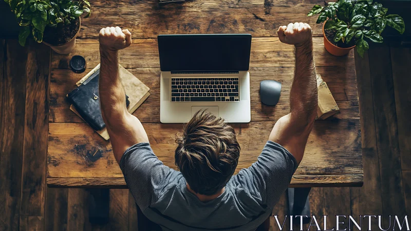 Remote worker celebrates success at rustic wooden workstation.