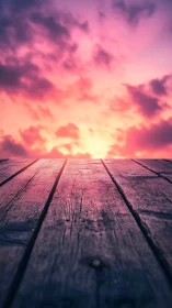Weathered wooden deck leads toward vivid pink sunset sky