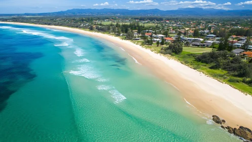 Aerial coastal panorama with turquoise surf and shoreline geometry.