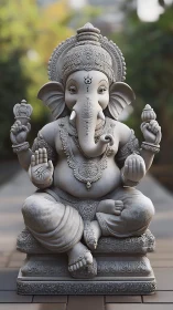 Stone Ganesha statue sits serenely on carved pedestal