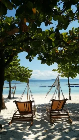Two hammock chairs on shaded tropical beach shoreline.