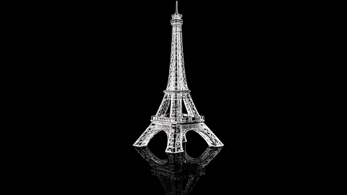 Metal Eiffel Tower model on reflective black background.
