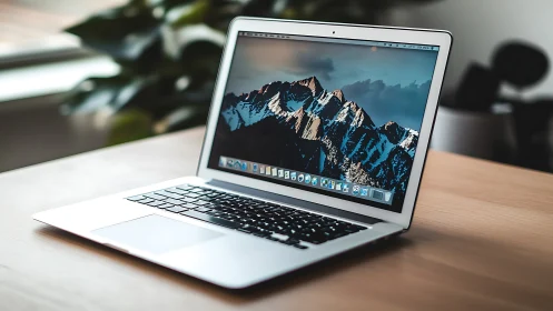 Aluminum laptop with mountain desktop on wooden workstation.