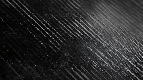 Diagonal graphite ridges forming dark abstract surface.