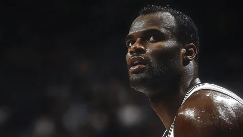 Sweat lit spotlight on focused basketball player courtside.