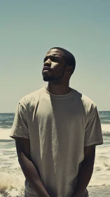 Man stands oceanside in hard midday sun, gaze upward.
