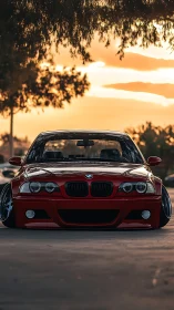 Lowered red BMW coupe glows under a cinematic sunset sky