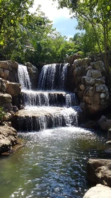 Sunlit garden waterfall tumbling into a tranquil rock pool.