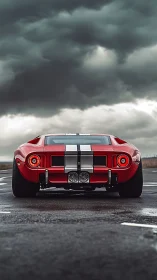 Low-angle rear view captures red racing car under storm clouds