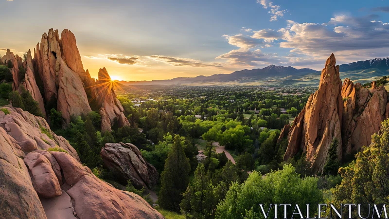 Sunlit red rock spires rise over a lush green valley at dusk