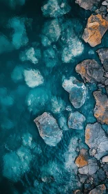 Rocky shoreline resting in calm teal and turquoise water.