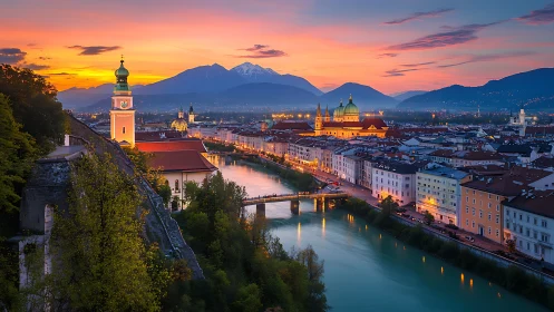 Central European river city at dusk with mountains visible.