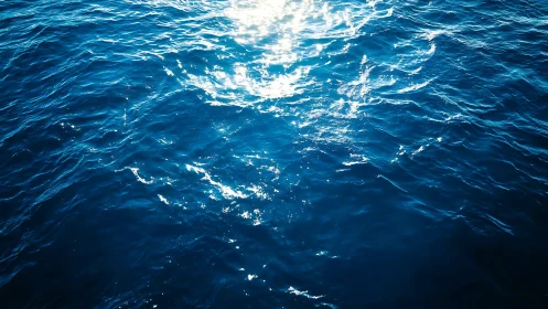 Sunlight reflects on deep blue ocean surface with small waves