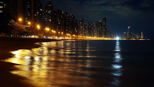 Coastal city skyline with illuminated seafront at night.
