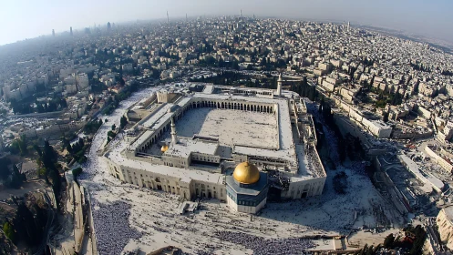 Aerial view of large mosque complex within dense cityscape.