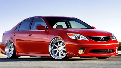 Red Toyota sedan with custom lowered stance and wheels.