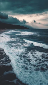 Moody stormfront over teal shoreline with foaming surf.