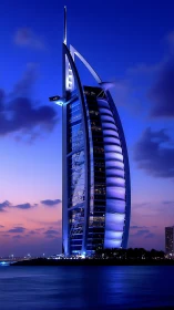 Sail-shaped waterfront skyscraper stands against dusk sky