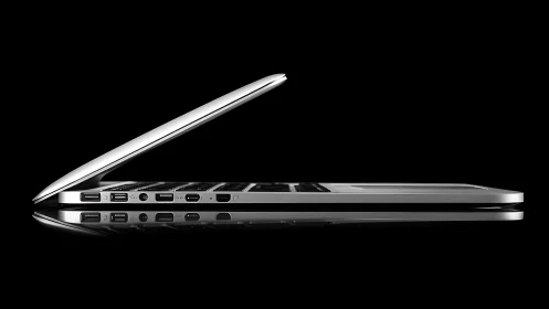 Ultrathin silver laptop in side profile under high-contrast studio lighting