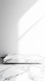 Marble display plinth under hard daylight in minimal interior.