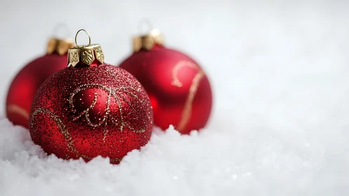 Red Christmas baubles rest in soft snow with festive sparkle