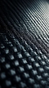 Carbon fiber weave in dramatic oblique close-up lighting.