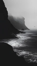Steep coastal cliffs meet rough ocean under heavy fog