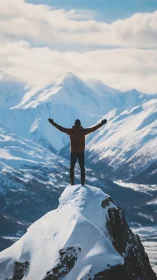 Hiker stands on snowy mountain peak facing distant ranges