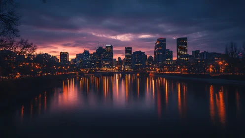 City skyline at dusk with river reflections and vivid glow.