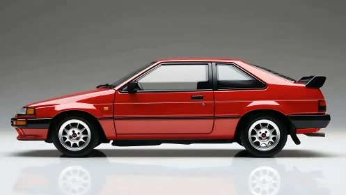 Side-profile red 1980s sport compact coupe on studio gray