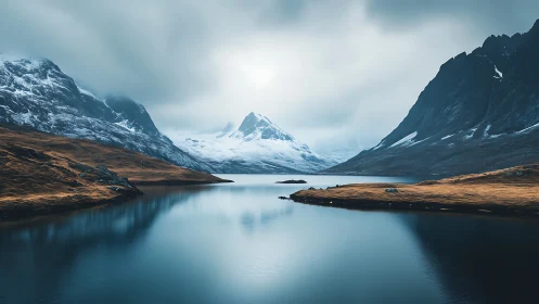 Cold alpine fjord with mirrored glacial peaks and low cloud cover