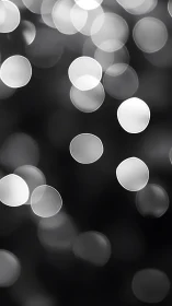 Soft monochrome bokeh orbs floating in blurred darkness.