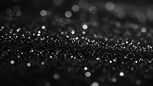 Black bokeh glitter field glows with soft luminous highlights.