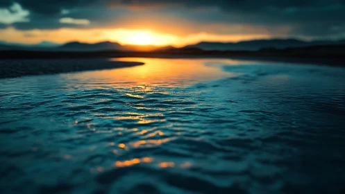 Low-angle view of rippled water under distant sunset horizon.