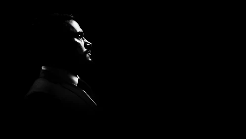 High-contrast profile portrait isolates a suited male subject