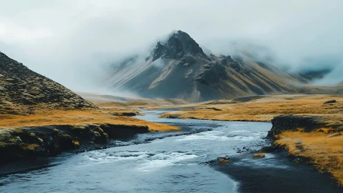 Fog-draped mountain rises above winding icy river valley.