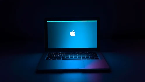 Low-key laptop product shot with cool neon rim lighting.