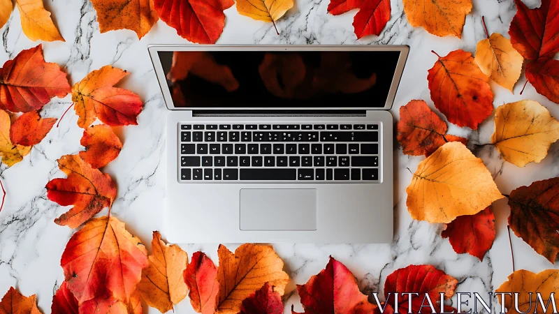 Open laptop rests centered amid vivid autumn leaves