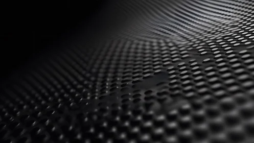 Abstract close-up of black perforated metal surface with soft lighting.