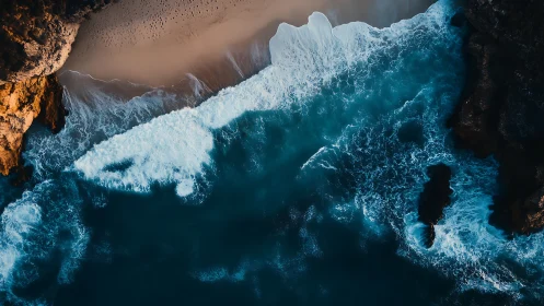 Overhead coastal surf against rocky cliffs and sand shore.